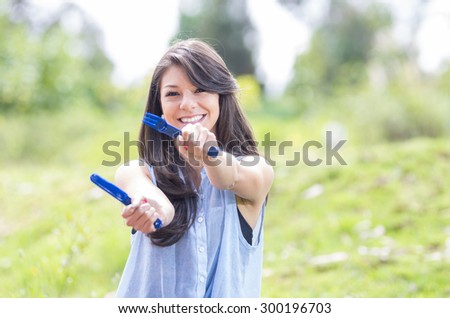 beautiful young girl holding a plastic knife and fork sitting on the grass of a park