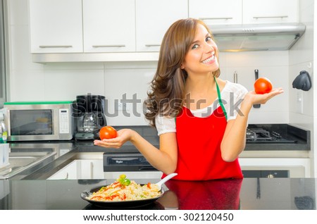 beautiful woman cooking in modern kitchen posing with tomatoes smiling to camera.