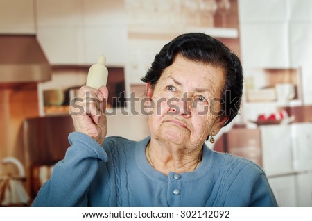 Older cute hispanic woman in blue sweater holding up a rolling pin.