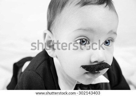 Cute beautiful baby boy in costume with mustache and suit white background close up