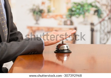 hand of businessman customer ringing hotel bell in reception desk close up selective focus
