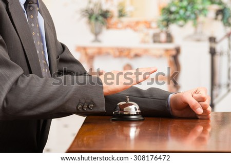 hand of businessman customer ringing hotel bell in reception desk close up selective focus