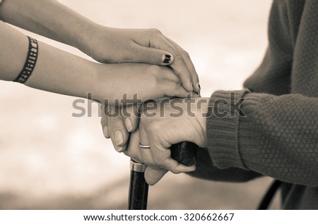 Closeup grandmother granddaughter holding hands, outdoors environment black and white edition.