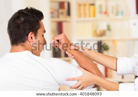 Male patient seen from behind with female physio therapist hands holding mans arm