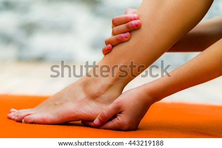 Woman touching her clean foot, one hand in a heel and other in her leg, background of orange color