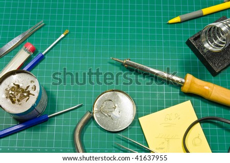 Different soldering hobby tools (soldering iron, solder, holder. pen, cutting mat, tweezers)  still life composition.