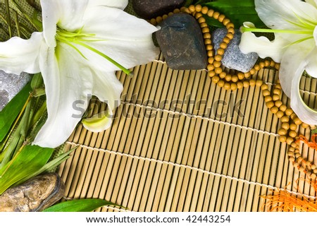Oriental abstract background (frame)  - beads, lily flowers, stones and bamboo leafs  on bamboo mat background.
