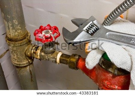 Sanitary equipment still life with old rusty tubes, brass valve with red cap, red and green water meter, white protective cloves and shiny metal wrench.