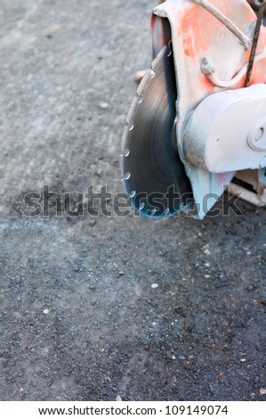 Construction machine used for cutting through concrete or tarmac roads. Focus on blade