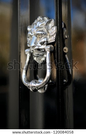 Old lion\'s head door knob on a black door in a London mansion