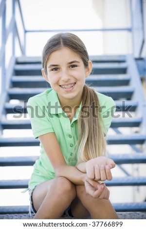 Portrait of Smiling Tween Girl Sitting On Stairway