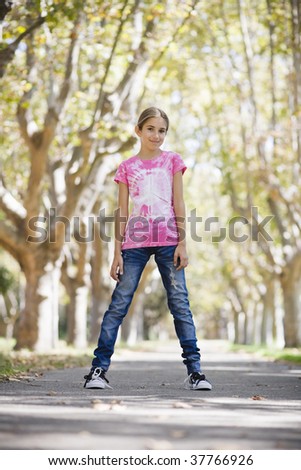 Portrait of Smiling Tween Girl Standing on Path in Park