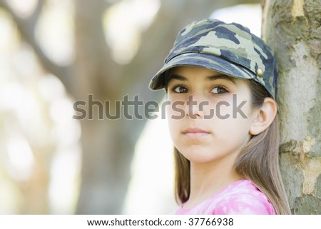 Portrait of Tween Girl In Cap Standing Against Tree