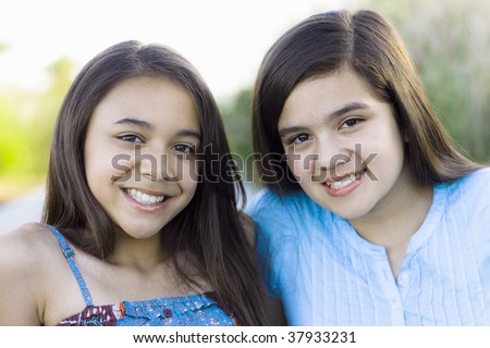 Two Tween Girls in a Park Smiling To Camera