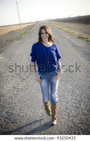 Pretty Young Woman Walking down the Middle of the Road in the Country