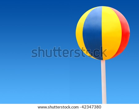 Big color beach ball on a blue sky. Looks like a sweet candy. Ball is isolated and clipping path included.