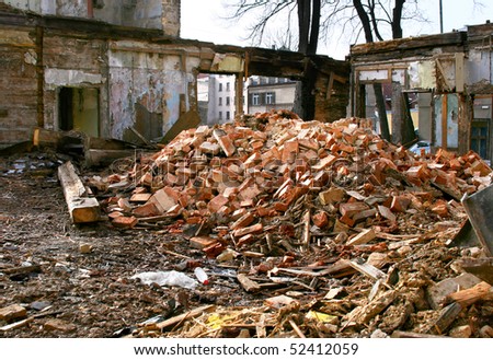 Demolished abandoned building with broken windows and wall in one of the street in center of Riga, Latvia. Bricks and many garbage of wooden boards in a front.