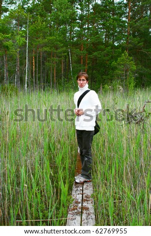 Young scary man is walking through narrow and wet hiking trail on a bog in Engure, Latvia