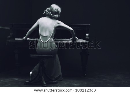 Beautiful young attractive woman in cocktail dress and piano