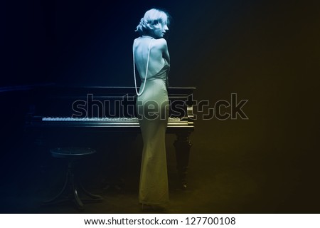 Beautiful young attractive woman in evening dress and piano