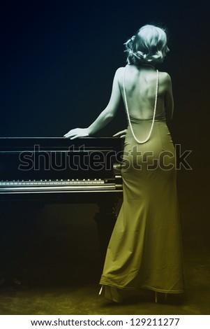 Beautiful young attractive woman in evening dress and piano