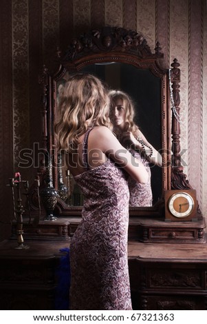 beautiful young woman looks at the reflection in the mirror in the vintage interior