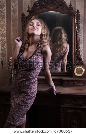 beautiful young woman looks at the reflection in the mirror in the vintage interior