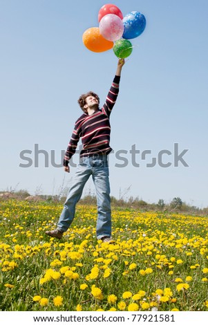 beautiful young man in a spring field with lots of balloons