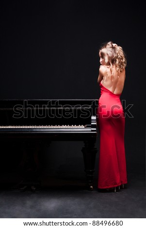 beautiful young attractive woman in evening dress and piano