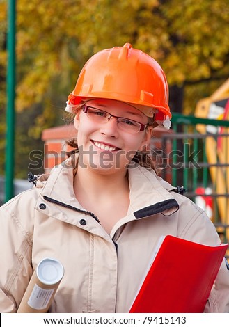 A female construction worker with building area behind