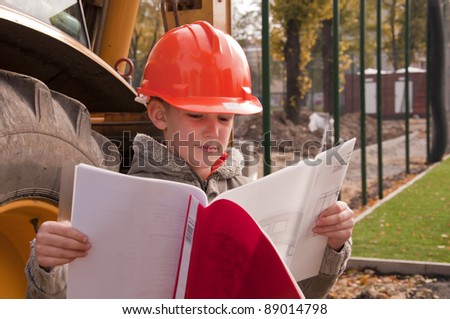 boy in helmet reading an architect`s plan