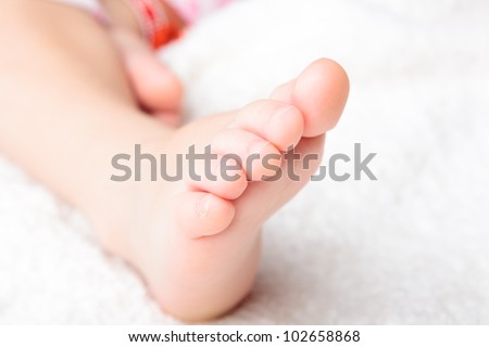 Baby\'s pretty legs on the white soft cover
