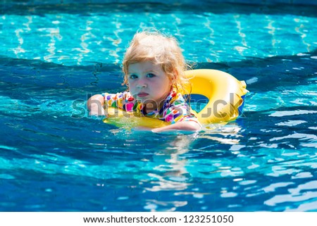 Little baby swimming in a pool on swimming ring