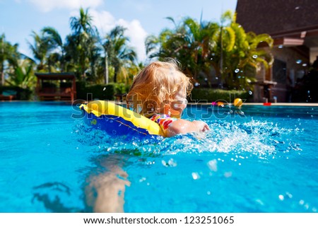 Little baby swimming in a pool on swimming ring