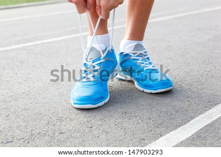 Closeup of Young Woman Tying Sports Shoe - concept image