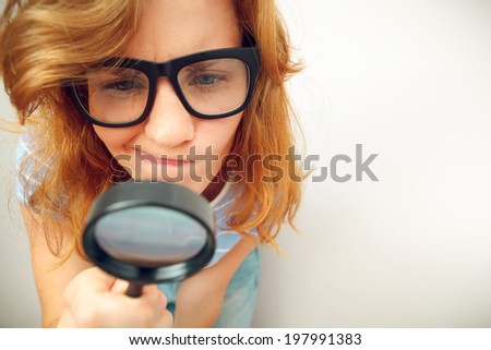 Young geek looking through magnifying glass.