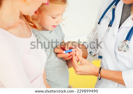 Doctor taking blood test from small patient.
