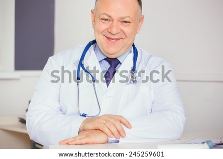 Doctor with stethoscope around his neck looking at the camera.