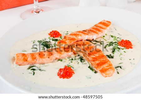 stock photo : Closeup of a salmon mini steaks laid on spinach with Bianco sauce