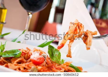 closeup of a fituchini served up with sauce and cherry tomatoes