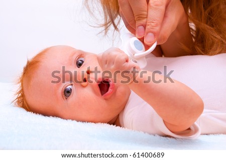 young mother trying to give baby`s dummy to her newborn baby