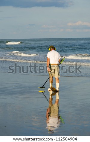 Senior citizen with the metal detector during the beach treasure hunt