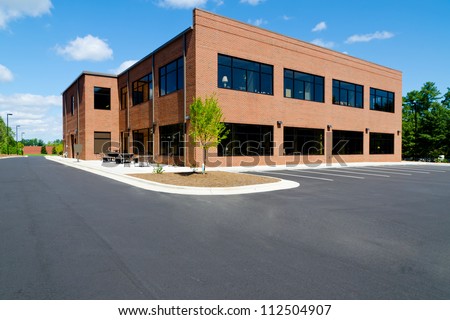Side View On The Generic Red Brick Office Building With Parking Lot