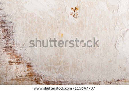 Grungy wooden board with beige and scratched plaster on the surface.