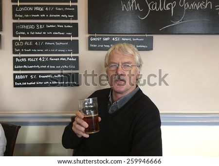 MALDON, ENGLAND 10TH JANUARY 2015: Man drinking a pint of real ale next to a list of the beers sold in the pub.  Small breweries making their own brands are increasingly popular in Britain