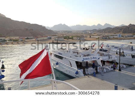 SHARM EL SHEIKH, EGYPT - JUNE 26 2015:  Dive boats with divers flag in the International Harbour, with the mountains of Sinai in the background. Diving and snorkelling are still very popular in Egypt.