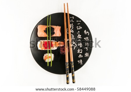 Smoked salmon and prawn nigiri and norimaki sushi garnished with red and black fish eggs and chives.  on a black japanese plate with Japanese script in white and red. On white with chopsticks.