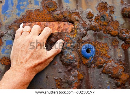 Hand grabbing at a rusted and very corroded painted metal from a wrecked fishing boat for grunge backgrounds