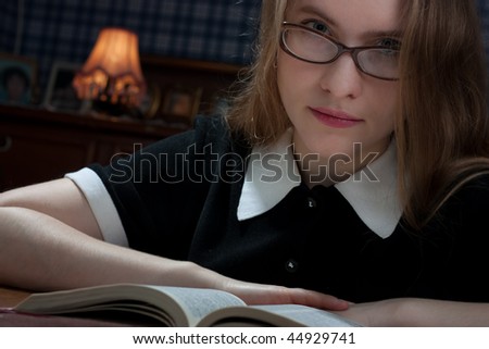 beautiful young woman with glasses reading book at the table