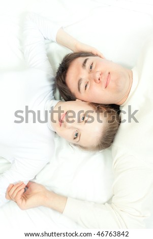 young man and woman lying on the bed and smiling